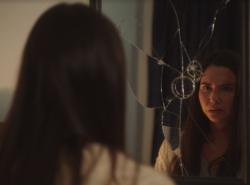 Actress Sera-Lys McArthur looks into a broken mirror