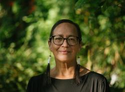 Dr. Nel Wieman stands in front of leafy trees