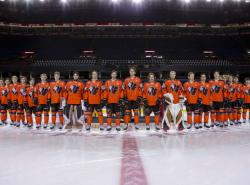 Calgary Hitmen dressed in orange Every Child Matters jerseys stand in a line at centre ice.