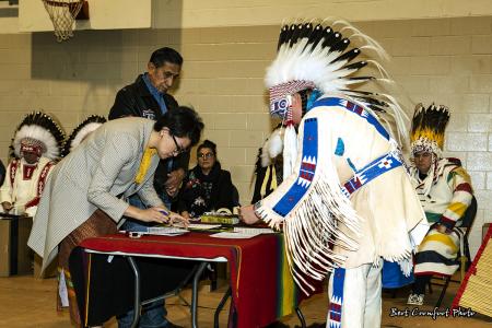 Councillor Kent Ayoungman signs official documents